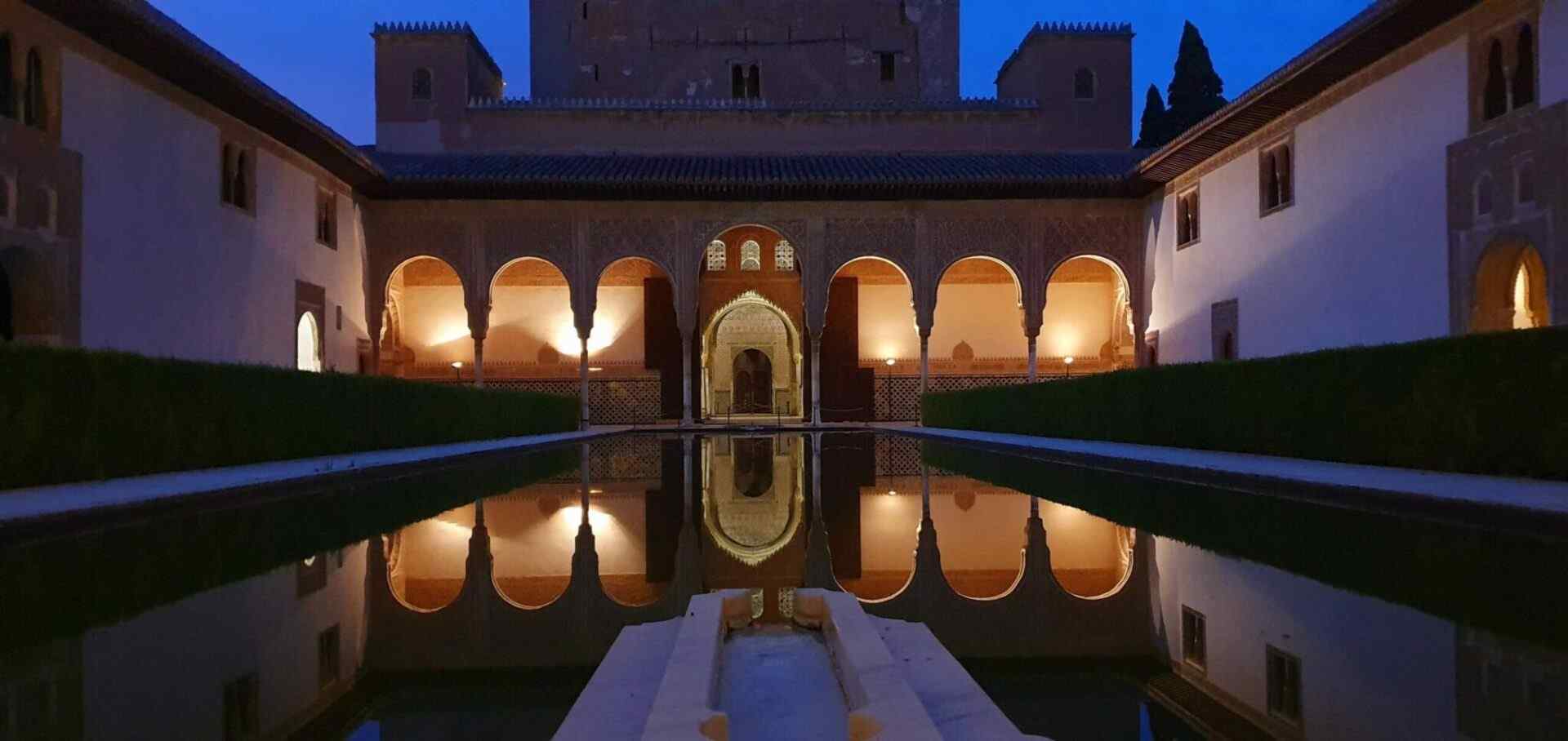 Visitatori esplorano il Patio de los Arrayanes sotto il colonnato del Palazzo di Comares, Alhambra