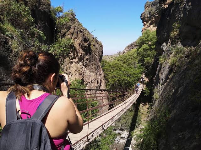 Hiker crossing a hanging bridge over the Rio Monachil gorge at Los Cahorros near Granada, Spain
