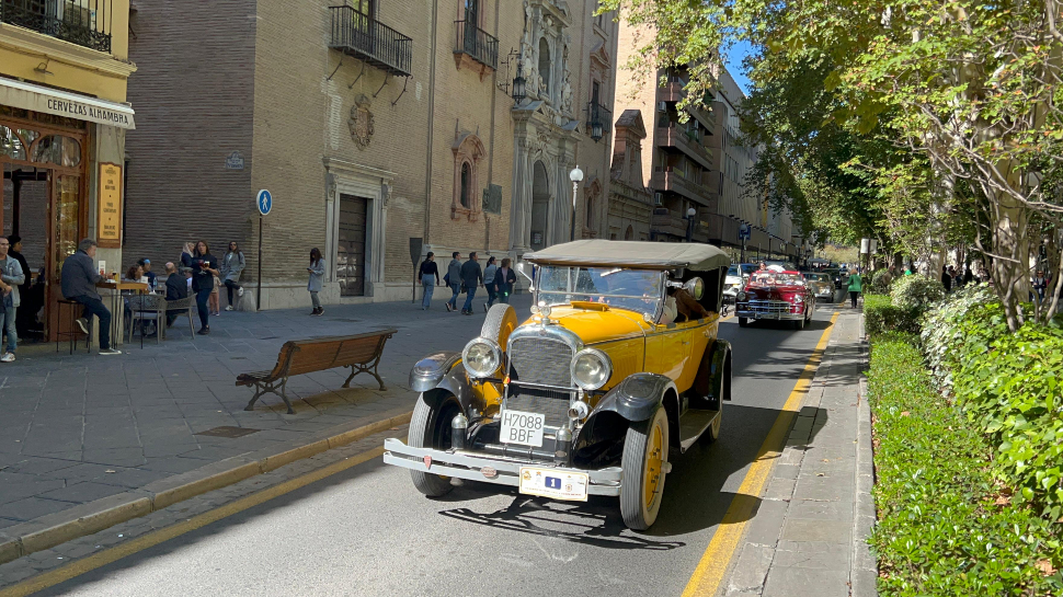 Narrow cobbled street in the Realejo neighbourhood of Granada, with parked cars visible on a residential street near the Alhambra